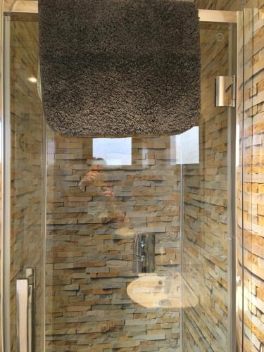 baño con lavabo y pared de piedra en Ade's River Cabin en Lettermacaward