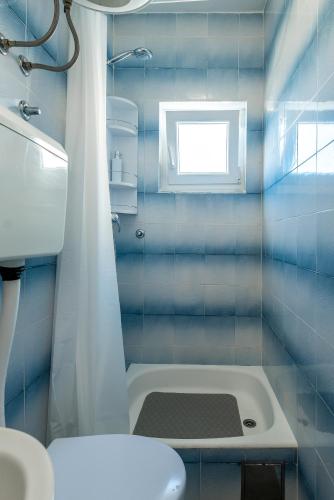 a blue tiled bathroom with a toilet and a window at Apartment and Rooms Dalmatiko in Vodice