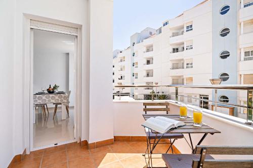 a apartment balcony with a table and chairs and a table and a building at Elegante piso en la Romanilla in Roquetas de Mar