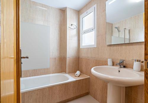 a bathroom with a tub and a sink and a mirror at Elegante piso en la Romanilla in Roquetas de Mar