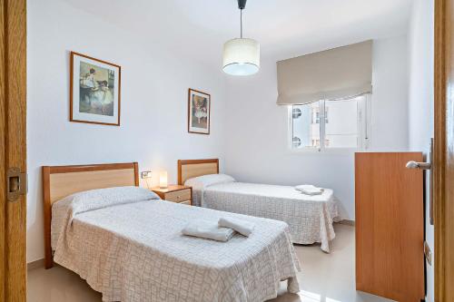 a bedroom with two beds and a window at Elegante piso en la Romanilla in Roquetas de Mar
