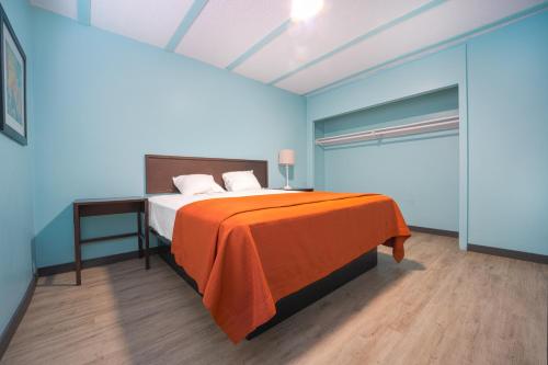a bedroom with a bed with an orange blanket at NOHO Hotel near Universal Studios Hollywood in Los Angeles