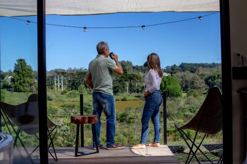 a man and woman standing on a stage looking out of a window at Casa Container - Haupt Village in Farroupilha