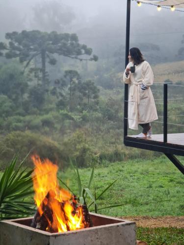 a woman taking a picture of a fire at Casa Container - Haupt Village in Farroupilha