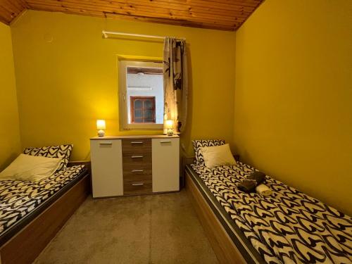2 Betten in einem Zimmer mit gelben Wänden in der Unterkunft Gebino apartman in Zamárdi