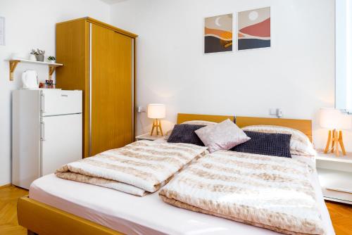 a bedroom with a bed and a refrigerator at Apartment and Rooms Dalmatiko in Vodice