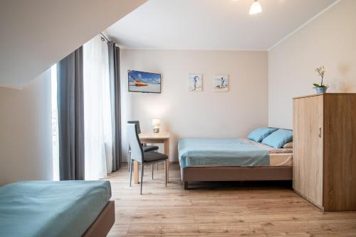 a bedroom with two beds and a desk and a chair at Barka Pokoje i Apartamenty in Karwia
