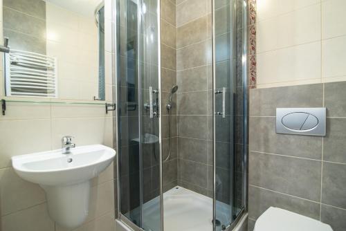 a bathroom with a shower and a toilet and a sink at Barka Pokoje i Apartamenty in Karwia