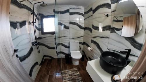 a bathroom with a toilet and a black sink at Stream House - Luxury living next to the river in Samothráki