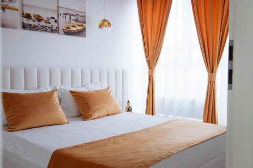a bed with orange and white pillows and a window at GoldenLux Apartments in Oradea