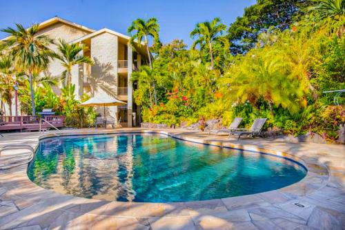 a swimming pool in front of a house with palm trees at Kalanikai 321 in Kailua-Kona