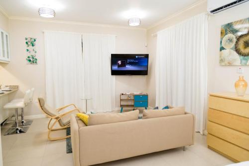 un soggiorno con un divano e una TV a parete di Choose To Be Happy at EI8HT! - Super Studios and Penthouse Apartment a Kingston