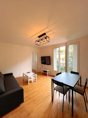 uma sala de estar com uma mesa e um sofá em APPARTEMENT SPACIEUX AVEC BALCON em Saint-Fons