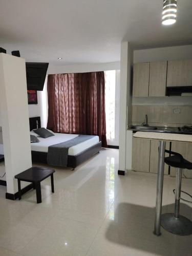 a bedroom with a bed and a table and a kitchen at Hotel Plaza Norte Cali in Cali