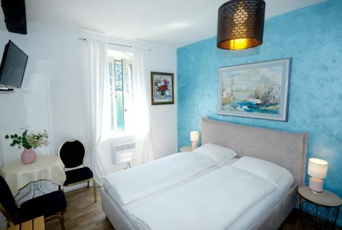 - une chambre avec un lit blanc et un mur bleu dans l'établissement Al Battello, à Morcote