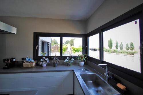 a kitchen with a sink and two large windows at Casa moderna a 300 metros de la playa. in Sant Josep de sa Talaia