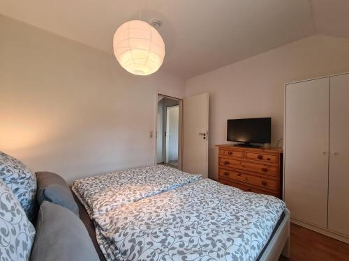 a bedroom with a bed and a dresser and a television at Ferienwohnung Sabrina in Nordleda