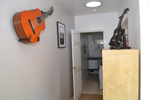 two guitars hanging on a wall in a room at Beautiful studio in Ely in Ely