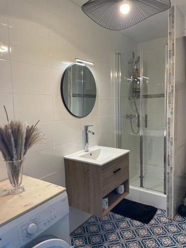 a bathroom with a sink and a shower with a mirror at Face Mer vue d'exception Studio rénové au 9ème étage in Les Sables-dʼOlonne