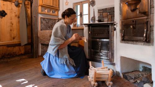 uma mulher sentada no chão em frente a um forno em Lutzmannhof em Irdning