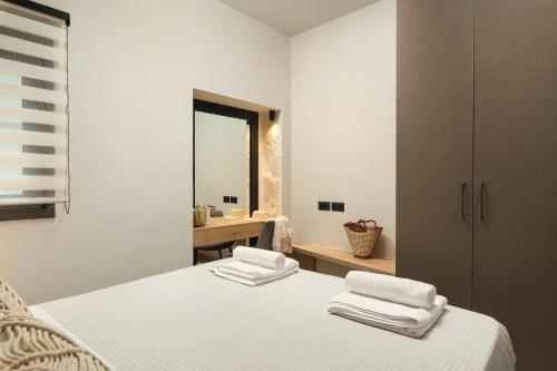 1 dormitorio con 1 cama con sábanas blancas y espejo en Limani elegant apartments, en Suda