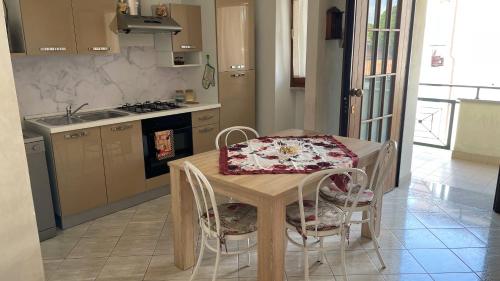 a kitchen with a wooden table with chairs and a sink at Rose e Frutta - Yellow Daisy in Ronchi dei Legionari