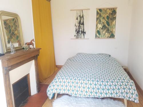 - une chambre avec un lit, une cheminée et un miroir dans l'établissement Maison de village, à Le Breuil-en-Auge