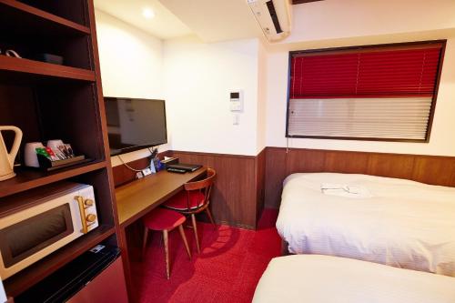 大阪市にあるHotel Sanriiott Kitahama - Vacation STAY 33534vのベッド、デスク、テレビが備わる小さな客室です。