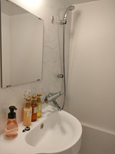 La salle de bains est pourvue d'un lavabo avec miroir et de bouteilles. dans l'établissement Hotel Sanriiott Kitahama - Vacation STAY 33534v, à Osaka