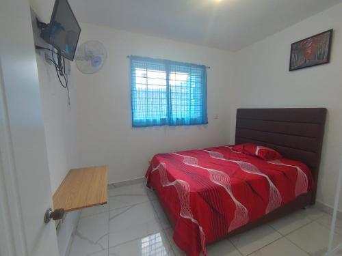 1 dormitorio con cama roja y ventana en Apartamento amueblado Res Blue Amber N1, en Santiago de los Caballeros