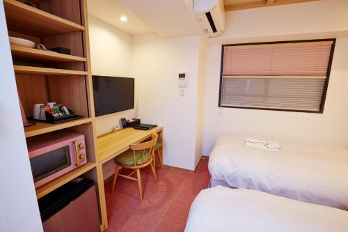 大阪市にあるHotel Sanriiott Kitahama - Vacation STAY 33534vのデスク、テレビ、ベッドが備わる小さな客室です。
