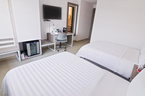 a hotel room with two white beds and a desk at GHL Style Yopal in Yopal