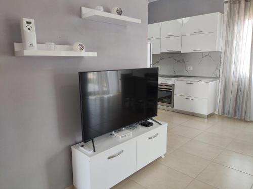 a white kitchen with a large flat screen tv at City View Apartments in Lezhë