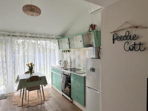 uma cozinha com armários verdes e um frigorífico branco em Peedie Cott Self-Catering, Orkney em St Margaret's Hope
