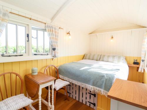 a bedroom with a bed and a table and chairs at Shepherds Hut at The Hollies in Woodbridge