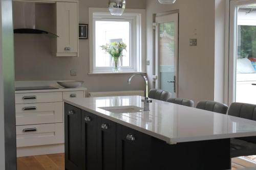 a kitchen with a sink and a counter with chairs at Gorgeous family home 15 mins from City Centre Edinburgh in Edinburgh