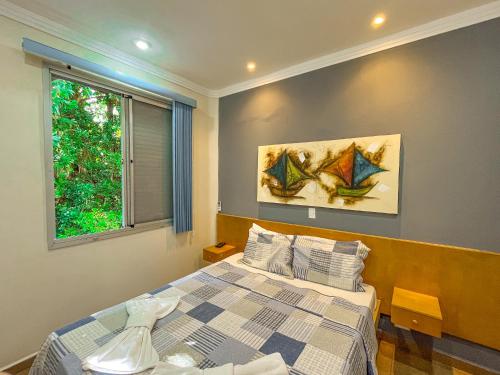 een slaapkamer met een bed en twee schilderijen aan de muur bij Hotel Nacional Inn Guarujá in Guarujá