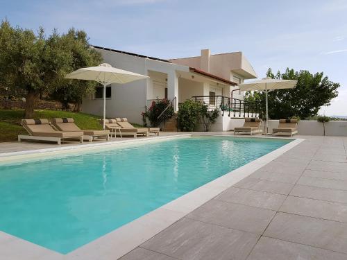 a swimming pool with chairs and umbrellas next to a house at Sithonian Villa in Neos Marmaras