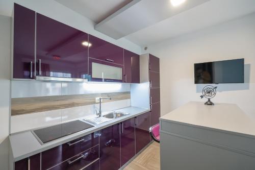 a kitchen with purple cabinets and a sink at Boutique Apartments Ad Astra in Bibinje
