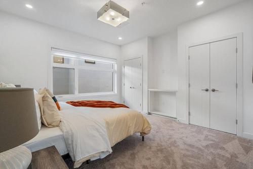 a white bedroom with a bed and a window at BEAUTIFUL, ELEGANT AND SPACIOUS 2 & HALF BR HOUSE in Calgary