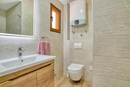 a bathroom with a sink and a toilet and a mirror at Seaview Villa Lavanda with pool in Budva