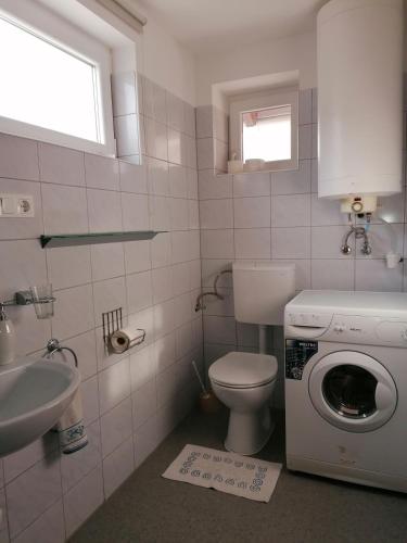 a bathroom with a washing machine and a sink at Marianna Apartman in Gyenesdiás