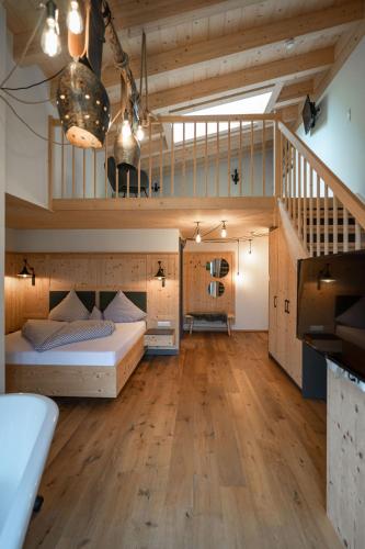 a large room with a bed and a staircase at Hotel Landhaus Tirolerherz in Sankt Ulrich am Pillersee