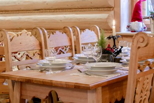 a wooden table with plates and wine glasses on it at Góralski Gościniec & SPA in Poronin