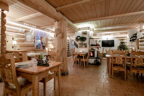 a restaurant with wooden tables and chairs and a television at Góralski Gościniec & SPA in Poronin