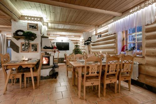 a dining room with a fireplace and a table and chairs at Góralski Gościniec & SPA in Poronin