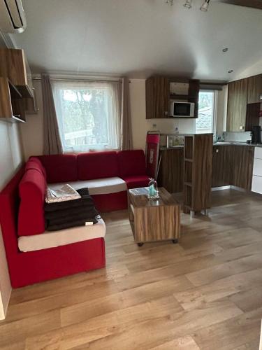 a living room with a red couch and a table at Camping les Cigales - Mobil-home 4/6 personnes in Le Muy