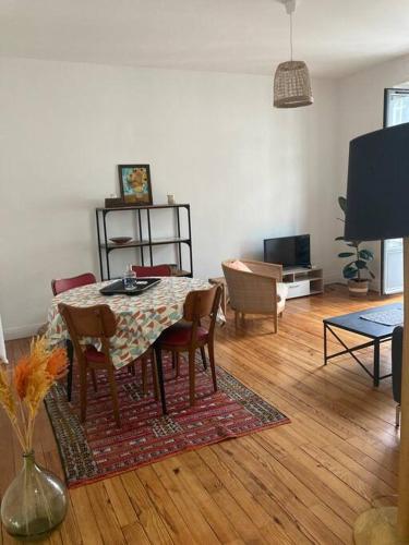 un salon avec une table, des chaises et une télévision dans l'établissement Appartement à 2 pas du château, à Pau