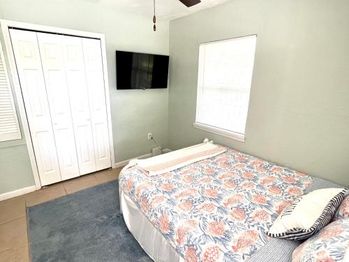 a bedroom with a bed and a tv and two windows at Beach Bungalow in downtown Cocoa Beach in Cocoa Beach