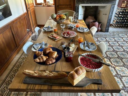 ein Holztisch mit Brot und Gebäck darauf in der Unterkunft Le Domaine des Volets bleus in Beuzeville